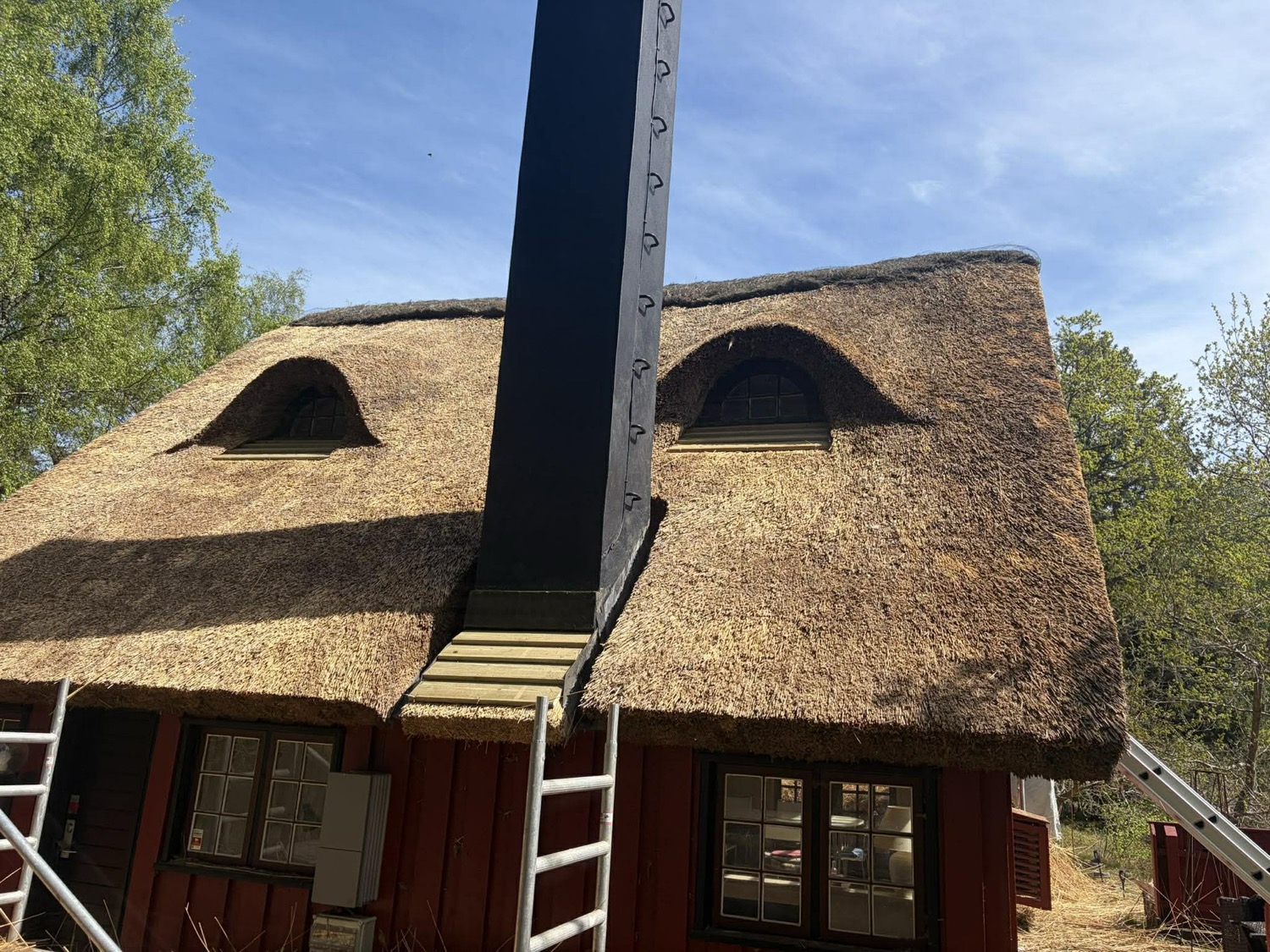 Sommerhusets renoverede stråtag med jævn tagflade og valmede kviste