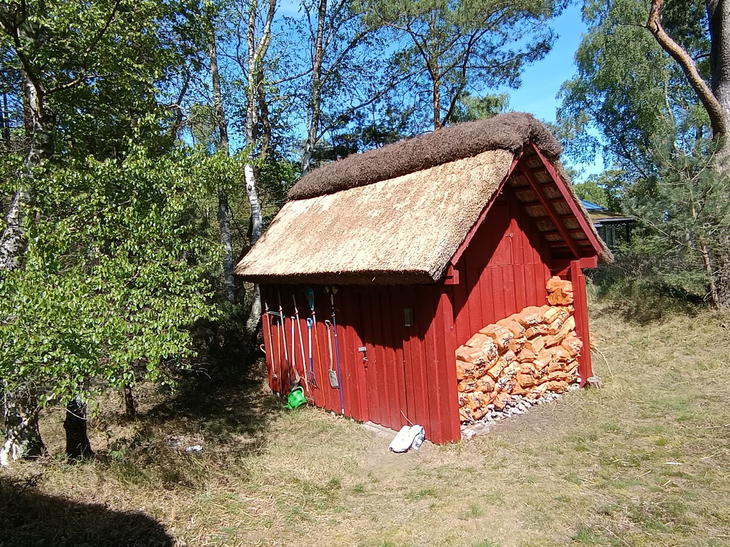 Det stråtækte udhus med ny lys tagflade og mørk lyngmønning